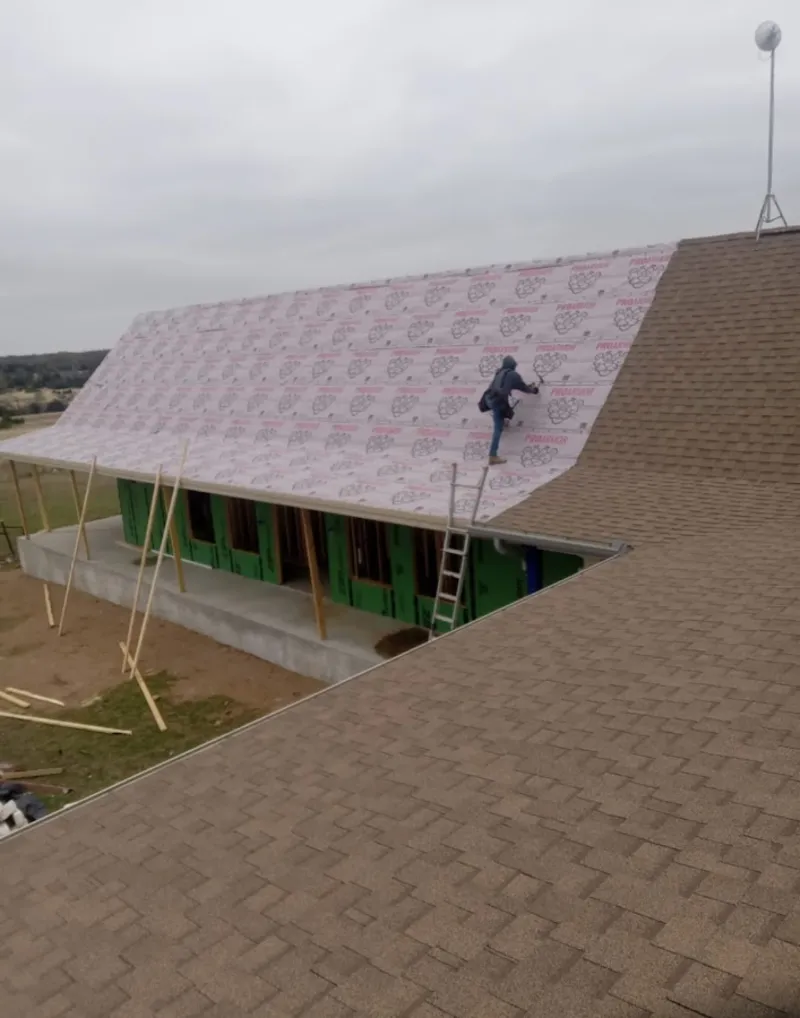 Worker preparing underlayment for a metal roof installation in Oak Point